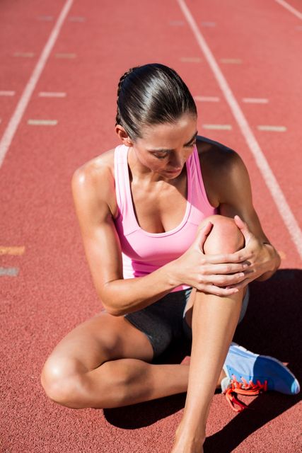 Female athlete with pain in knee joint on running track - Download Free Stock Photos Pikwizard.com