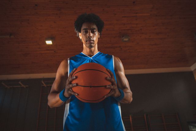 Portrait of mixed race male basketball player holding basketball in two hands - Download Free Stock Photos Pikwizard.com