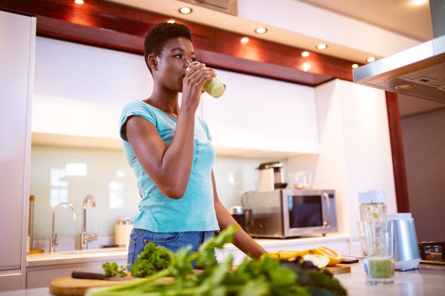African american woman drinking fresh smoothie in kitchen - Download Free Stock Photos Pikwizard.com