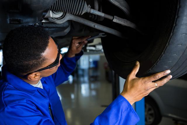 Attentive mechanic examining car tyre at repair garage