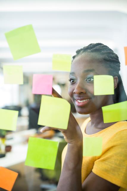 Female graphic designer looking at sticky notes in office