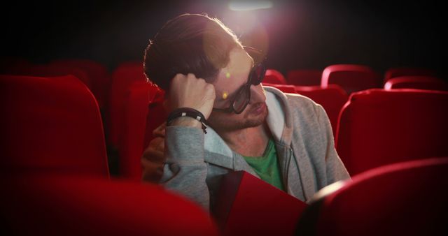 A man appears stressed in a theater, possibly due to a film's intense scene. - Download Free Stock Photos Pikwizard.com