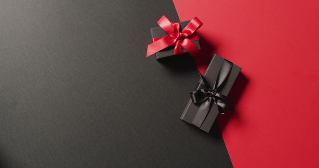 Overhead view of two black gift boxes with red and black ribbons on black and red with copy space - Download Free Stock Photos Pikwizard.com