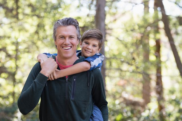 Portrait of happy father piggybacking son while hiking in forest