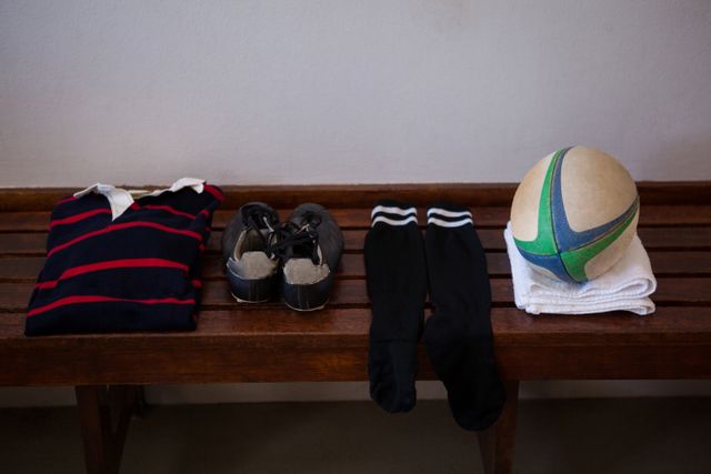 High angle view of clothes and rugby ball on wooden bench against wall