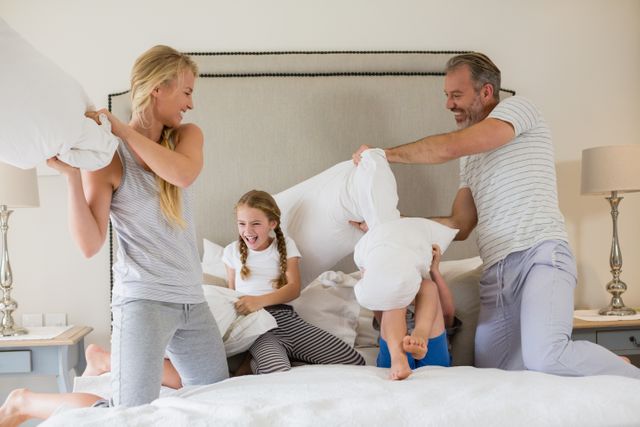 Cute family having a pillow fight in bedroom - Download Free Stock Photos Pikwizard.com