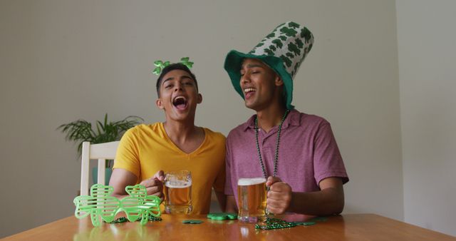 Mixed race gay male couple making st patrick's day image call raising glasses wearing costumes. staying at home in isolation during quarantine lockdown.