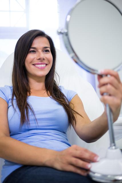 Smiling patient looking in the mirror at clinic