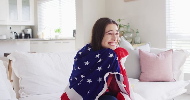 Happy caucasian woman sitting on couch with flag of usa and watching tv in living room. Spending quality time at home concept.