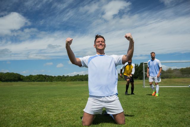 Excited football player in celebrating scoring goal kneeling on grass pitch - Download Free Stock Photos Pikwizard.com