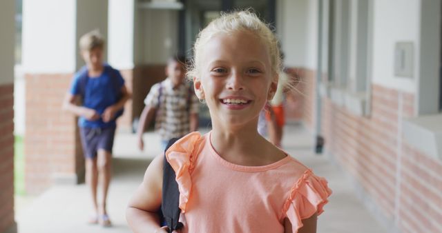 Image of happy caucasian girl standing at school corridor. primary school education and learning concept.