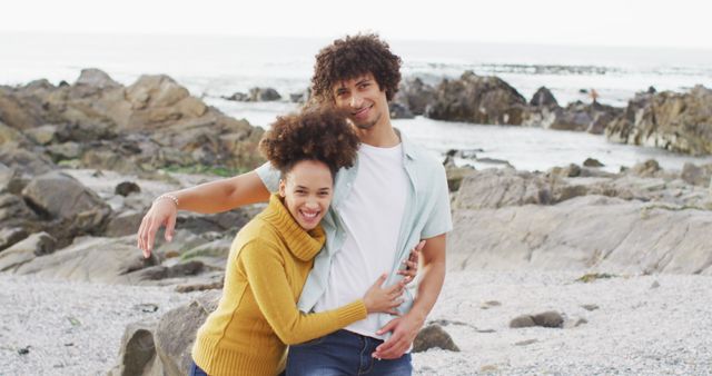 Portrait of african american couple hugging each other on the rocks near the sea. love and relationship concept