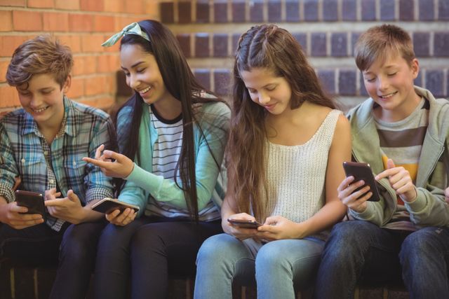 Group of smiling school friends sitting on staircase using mobile phone - Download Free Stock Photos Pikwizard.com