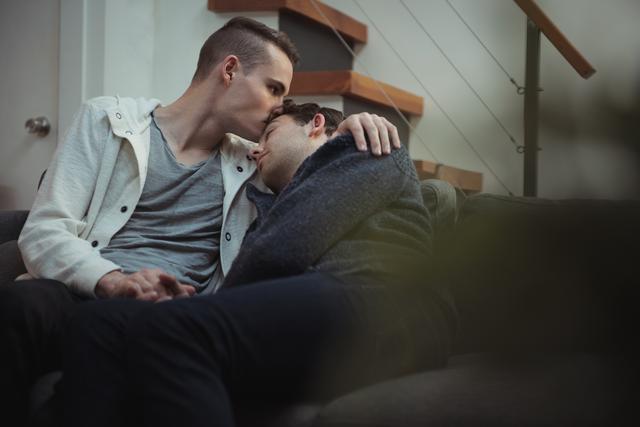 Gay couple kissing and embracing on sofa - Download Free Stock Photos Pikwizard.com