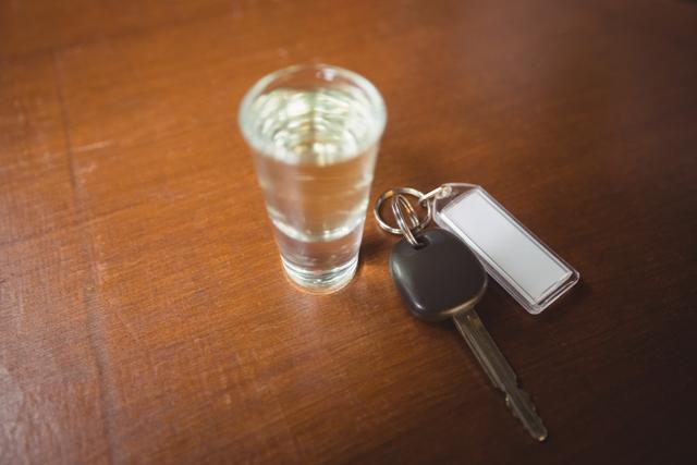 Glass of tequila shot with car key in bar counter at bar