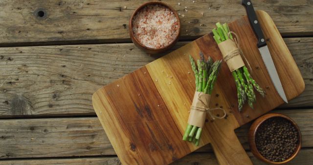 Image of two fresh asparagus bundles on wooden chopping board with knife and salt and pepper - Download Free Stock Photos Pikwizard.com