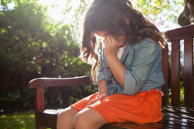 Upset girl crying while sitting on wooden bench - Download Free Stock Photos Pikwizard.com