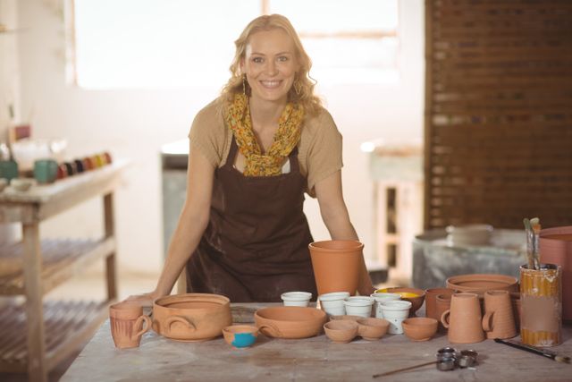 Beautiful female potter leaning on worktop - Download Free Stock Photos Pikwizard.com