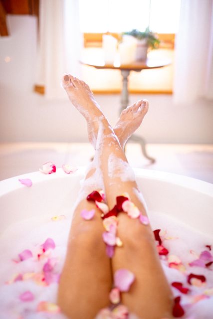Feet of mixed race woman relaxing in bath with foam and flower petals - Download Free Stock Photos Pikwizard.com