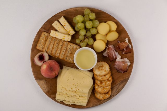 Different types of cheese, crispy biscuits, fruits and sauce on wooden board - Download Free Stock Photos Pikwizard.com