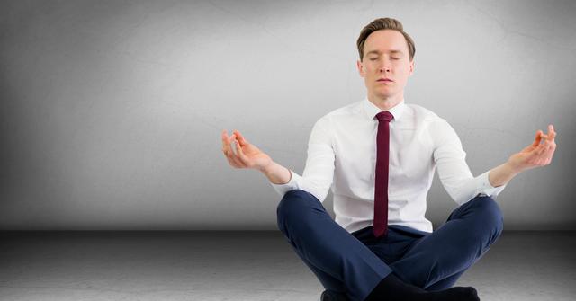 Business man meditating in grey room - Download Free Stock Photos Pikwizard.com