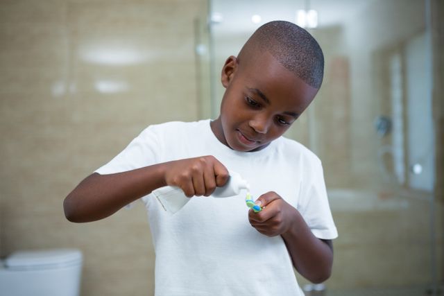 Boy removing toothpaste on brush at domestic bathroom