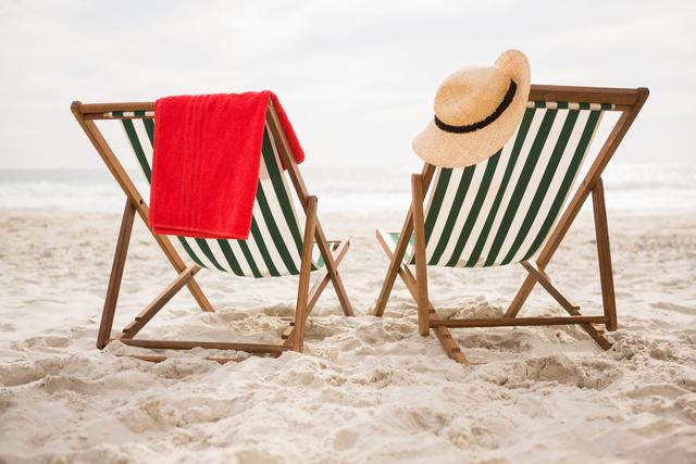 Straw hat and towel kept on beach chairs - Download Free Stock Photos Pikwizard.com