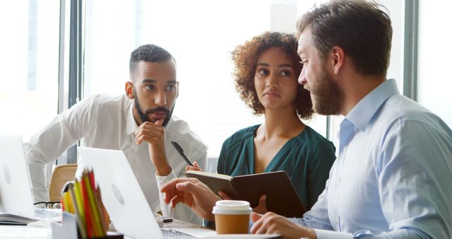 Busy biracial colleagues discussing work with latpop in office from ...