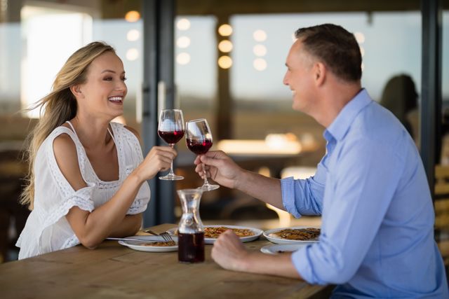 Happy couple toasting wine glass while having meal - Download Free Stock Photos Pikwizard.com