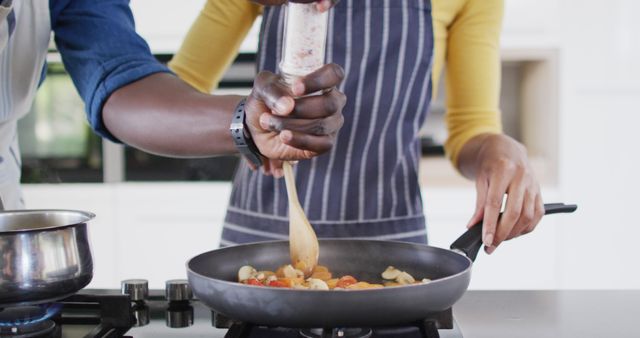 Image of midsection of african american couple cooking together. Love, relationship and spending quality time together concept.