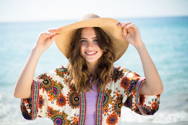 Happy young woman wearing hat while standing at beach - Download Free Stock Photos Pikwizard.com