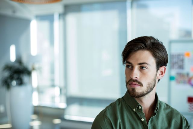 Thoughtful man looking away in office