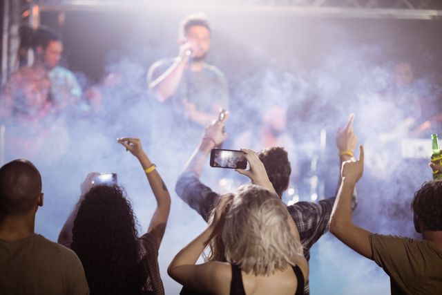Rear view of fans enjoying music concert at nightclub