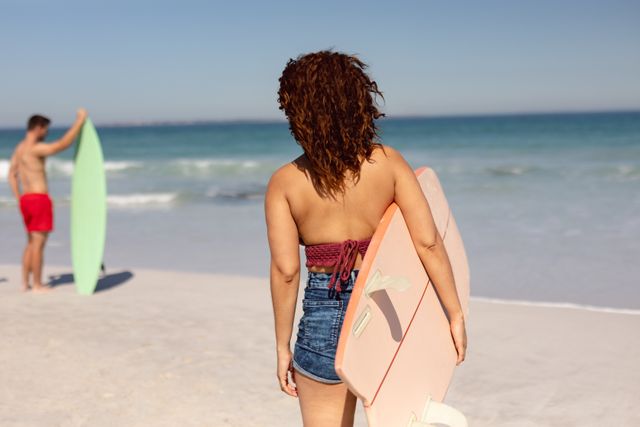 Woman with surfboard standing on beach in the sunshine - Download Free Stock Photos Pikwizard.com