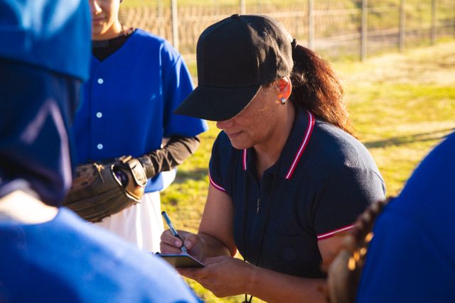 Diverse group of female baseball players with coach, discussing game tactics - Download Free Stock Photos Pikwizard.com