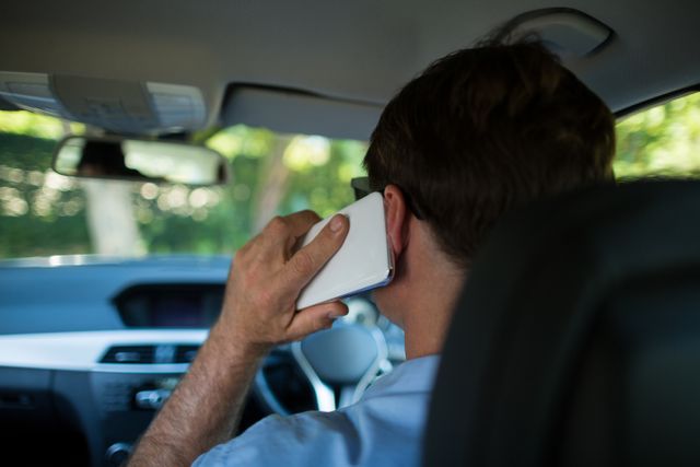 Rear view of man talking on phone while driving car
