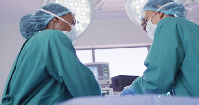 Low angle image of two diverse female surgeons talking during operation in theatre. Hospital, medical and healthcare services.