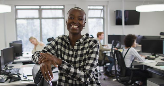 Portrait of smiling african american creative businesswoman sitting by desk in modern office. business and office work environment.