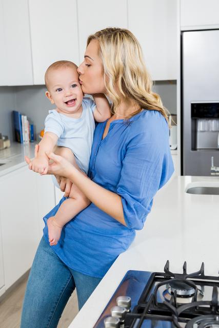 Mother holding her baby boy in kitchen - Download Free Stock Photos Pikwizard.com