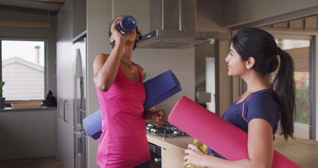 Image of happy diverse female friends holding yoga mats and talking at home. Friendship, spending quality time together at home.