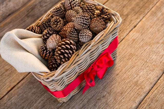 Pine cones in wicker basket tied with red ribbon on wooden plank - Download Free Stock Photos Pikwizard.com