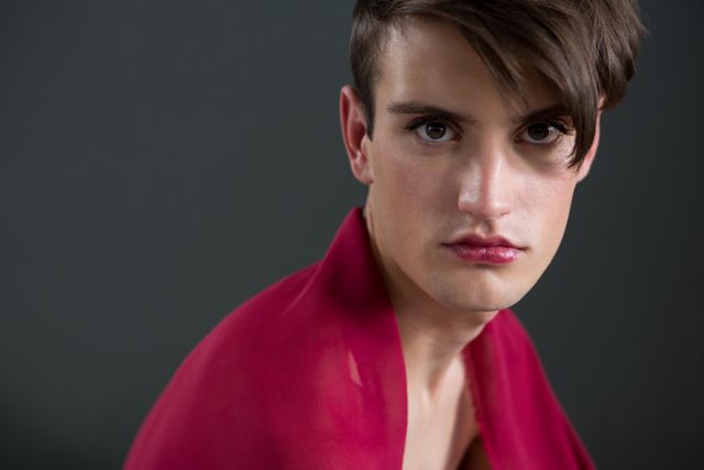 Portrait of androgynous man wrapped in red clothes against grey background
