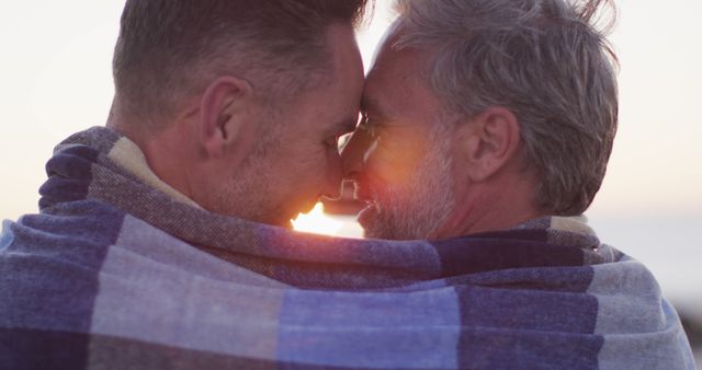 Happy caucasian gay male couple wearing blanket, embracing and taking selfie at sunset on the beach - Download Free Stock Photos Pikwizard.com