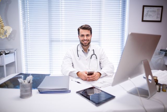 Portrait of male doctor sitting at desk in clinic