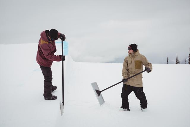 Two men cleaning snow in ski resort - Download Free Stock Photos Pikwizard.com