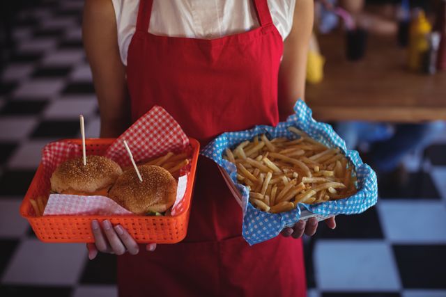 Waitress holding burger and french fries in tray - Download Free Stock Photos Pikwizard.com