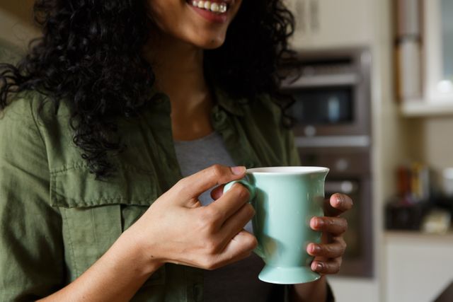 Mixed race woman drinking a cup of coffee and smiling - Download Free Stock Photos Pikwizard.com