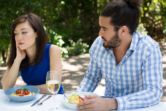 Young man looking at upset woman at outdoor restaurant