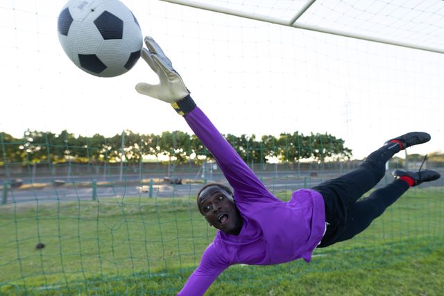 African american goalkeeper jumping and catching soccer ball in mid-air while defending goal - Download Free Stock Photos Pikwizard.com