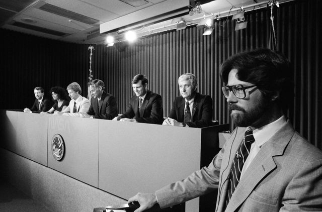 S84-40185 (08/21/1984) --- stronaut preflight Press Conference with the STS-41D Crew with Public Affairs Office (PAO) Reprentative Steve Nesbitt in the foreground in the Bldg 2 Briefing Room on 08/17/1984. Crewmembers visible (R-L) are: Henry W. Hartsfield, Jr., Crew Commander; Michael L. Coats, Pilot: Richard M. (Mike) Mullane, Steven A. Hawley, Judith A. Resnik - all Mission Specialists: and, Charlie D. Walker, Payload Specialist. JSC, Houston, TX
